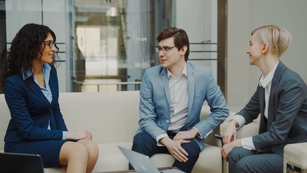 Three professionals engage in discussion in a modern office setting, promoting collaboration and teamwork in a business context.
